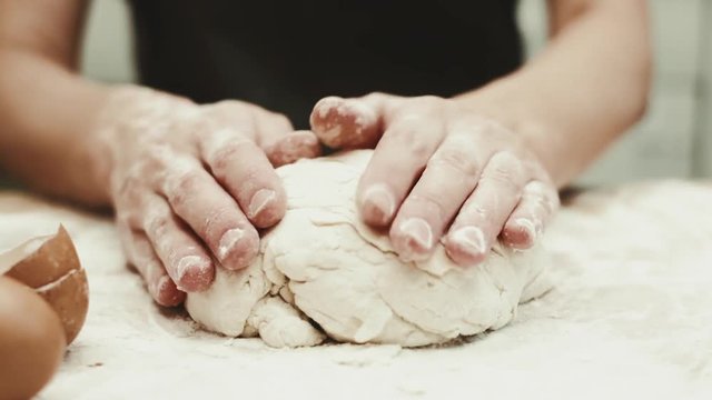 Close-up footage of female kneading raw dough, cooking bread at home. 