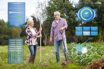 senior couple with shovels at garden or farm