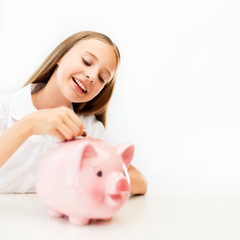 happy smiling girl putting coin into piggy bank