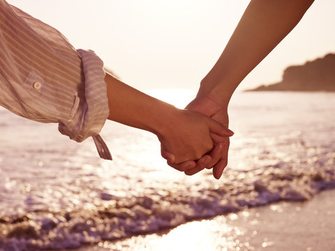 young couple holding hands on beach