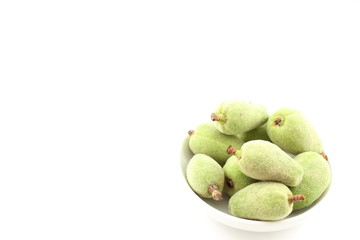 fresh green almond fruits in a small white bowl