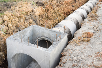 Concrete drainage pipe and manhole in construction site. - obrazy, fototapety, plakaty