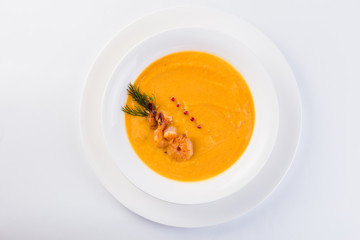 Fresh Creamy seafood soup with shrimps on a white plate on a light background (close top view)