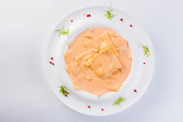 Ravioli stuffed on a white plate on a light background (close)