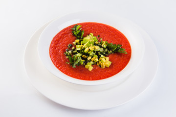 Spanish soup gazpacho with avocado and cucumber on a white plate on a light background