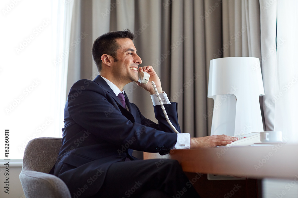 Poster businessman calling on desk phone at hotel room