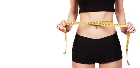 Slim female measuring her thin waist with a tape measure isolated on white.