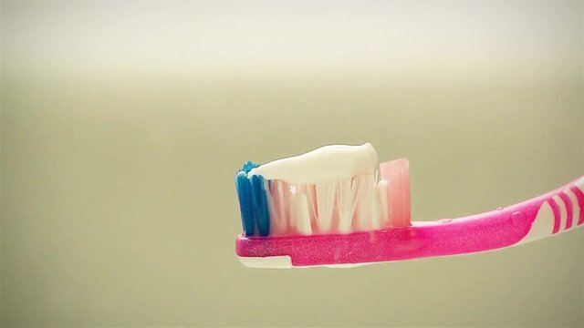 Young Man holding Toothpaste on a Toothbrush in Bathroom. Close Up.