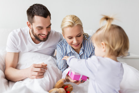 happy family with gift box in bed at home