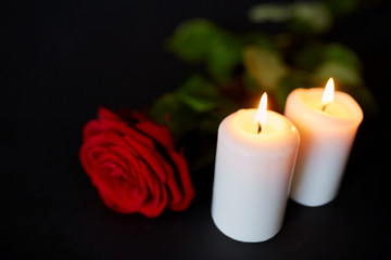 red rose and burning candles over black background