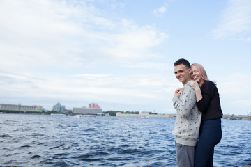 Young couple hugging and smiling on the background of the urban landscape. River embankment in Saint Petersburg