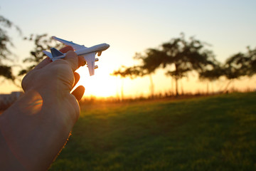 Fototapeta na wymiar close up of man's hand holding toy airplane against sunset sky