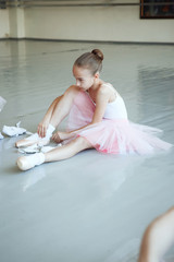 Cute little ballerina in pink ballet costume and pointe shoes is dancing in the room. Kid in dance class. Child girl is studying ballet. Copy space.