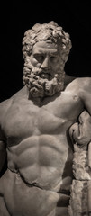 Statue of powerful Hercules, closeup, isolated at black background