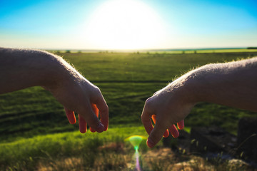Hands on the background of green field