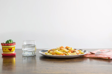 Food is in the plate, a glass of water, a spoon and flower vase on the wood table over white background-Restaurant business, health care and fast food concept.