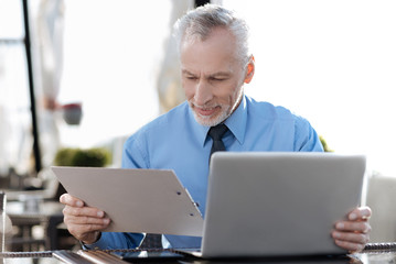 Fototapeta premium Positive delighted male person turning his head to folder