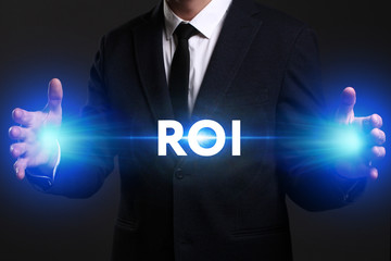 Business, Technology, Internet and network concept. Young businessman working on a virtual screen of the future and sees the inscription: ROI