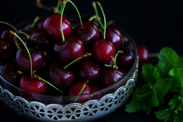 Fresh cherries in a cup on the table. Dark background. Selective focus.