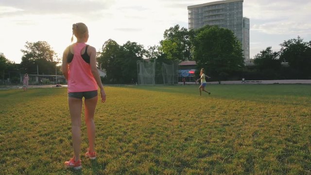 Two young and beautiful women playing frisbee in the park, slow motion