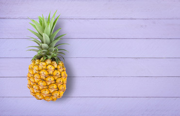 Pineapple on the light violet wooden table.