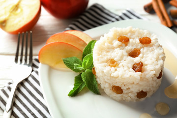 Plate with sweet rice and apple slices on on table, closeup