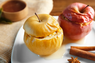 Plate with tasty baked apples and cinnamon on table, closeup