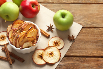 Composition with apple chips and cinnamon on wooden table