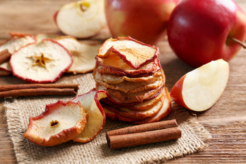 Composition with tasty apple chips and cinnamon on wooden table, closeup