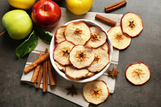Composition with apple chips and cinnamon on grey table