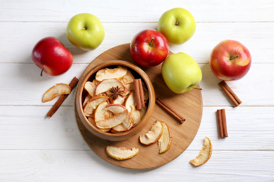 Composition with tasty apple chips and cinnamon on light wooden table