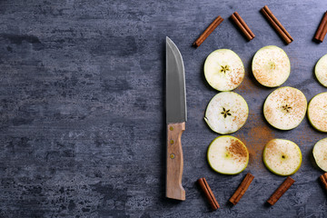 Composition with fresh cut apples, cinnamon and knife on wooden table