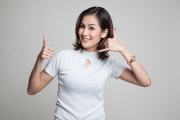 Young Asian woman thumbs up show with phone gesture.