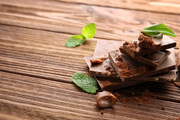 Dark chocolate pieces with mint leaves on wooden table