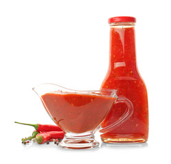 Bottle and gravy boat with tasty chili sauce on white background