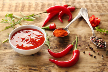 Tasty chili sauce in bowl on wooden table