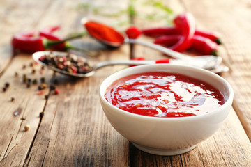 Tasty chili sauce in bowl on wooden table