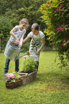 Two girls gardening, watering flowers together