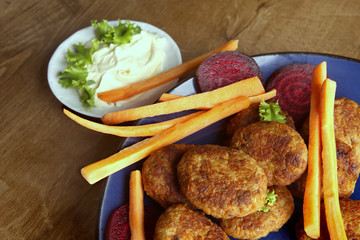 Fish cutlets with carrots, beetroots and mayonnaise sauce.  Homemade fried  cutlets in plate on wooden table.