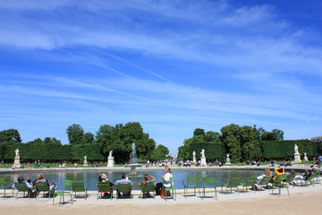 People relaxing in Tuileries Palace open air park with the view to Champs Elysees and Arc de...