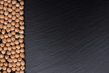 Chickpeas lies on a black stone board, space for text, black background
