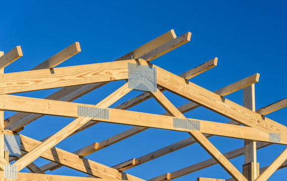 A New Build Roof With A Wooden Truss Framework With A Blue Sky Background.