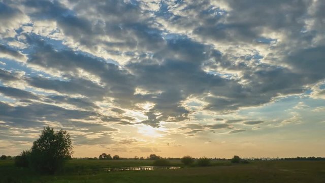 Beautiful clouds on a background of green grass in the rays of sunset. Time lapse video 1920 × 1080