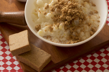 Brazilian dessert sweet canjica of white corn with pacoca sweet in bowl and towel. Festa Junina Party Brazilian Culture Concept Image.