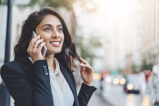 Young business woman walking and calling to colleagues with the city on the background