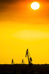 Obraz na płótnie Canvas SEVILLE SPAIN - JUNE 25: Landscape of a cranes in a harbor at sunset with clouds on June 25 2017 in Seville, Andalusia, Spain.