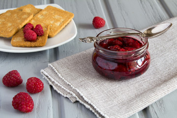 Raspberry jam and cookies on the grey wooden background