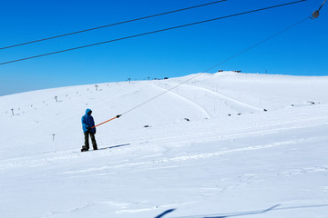 Fototapeta na wymiar snowboarder climbs a lift on a mountain against a blue sky