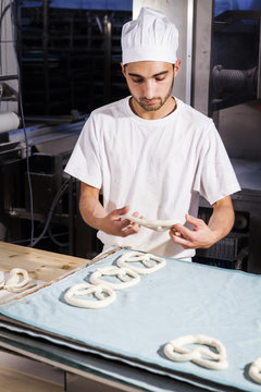 Baker shaping pretzel dough in bakery
