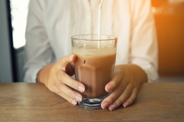 woman hands with ice chocolate on a wood table